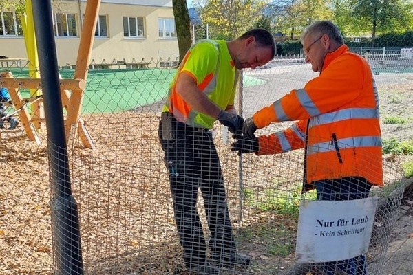 2 Mitarbeiter des Verbandsbauhofs beim Aufstellen der Laubk&ouml;rbe