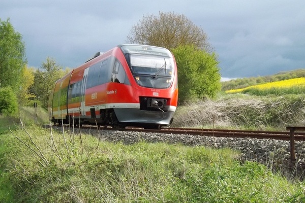Roter Nahverkehrszug der Deutschen Bahn fährt durch grüne Landschaft Roter Nahverkehrszug der Deutschen Bahn fährt durch grüne Landschaft