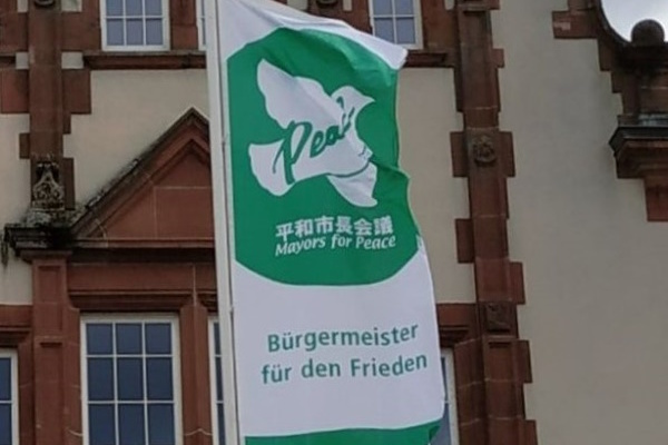Eine grüne Flagge mit der Aufschrift "Bürgermeister für den Frieden"