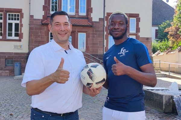 Foto v.l.n.r.: B&uuml;rgermeister Markus Hollemann und Christian Onuchukwu, der einen Fu&szlig;ball in seiner Hand h&auml;lt