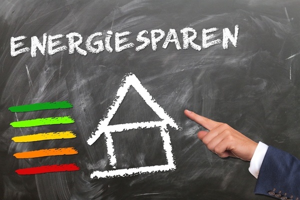 Eine Hand zeigt auf eine Strichzeichnung eines Hauses mit einem Energielabel daneben Eine Hand zeigt auf eine Strichzeichnung eines Hauses mit einem Energielabel daneben