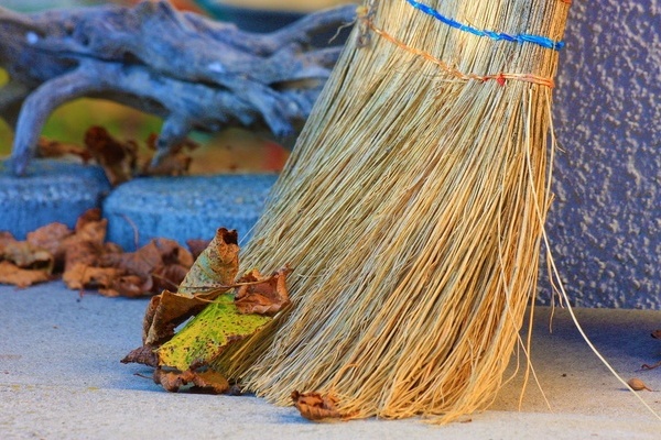 Herbstlaub auf einer Stra&szlig;e, ein Besen