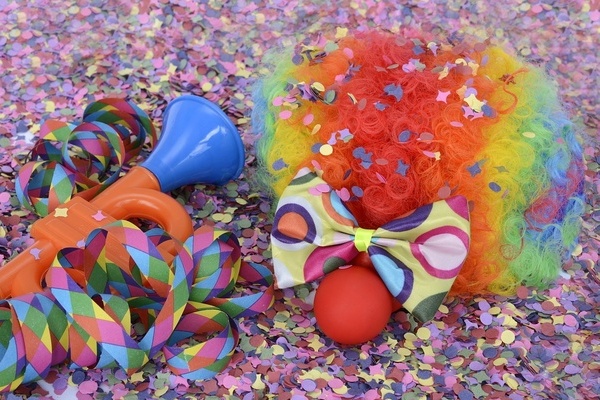 Buntes Konfetti, rote Lockenperücke, Fliege, Luftschlangen, Clownnase und Spielzeug Trompete Buntes Konfetti, rote Lockenperücke, Fliege, Luftschlangen, Clownnase und Spielzeug Trompete
