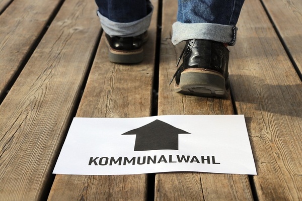 Schild mit schwarzer Schrift auf weißem Grund. Füße mit Schuhen. Schild mit schwarzer Schrift auf weißem Grund. Füße mit Schuhen.