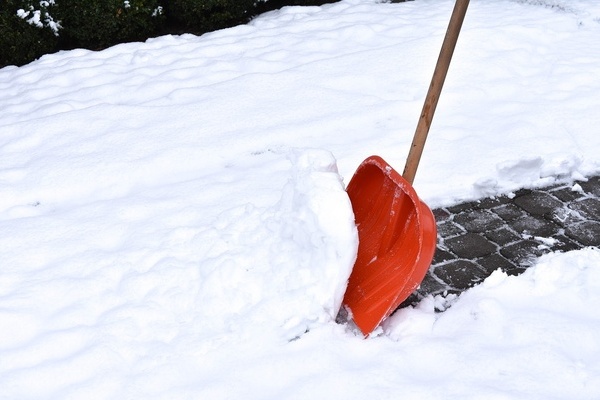 Beim Schneeräumen mit roter Schneeschaufel Beim Schneeräumen mit roter Schneeschaufel