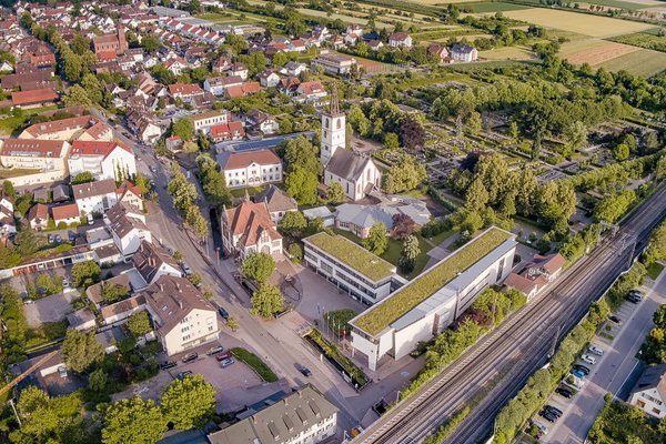 Luftbild mit Rathaus, evangelischer Kirche St. Georg mit Friedhof und Grundschule Standort Hauptstraße sowie Kohlerhof mit Bahnschienen DB